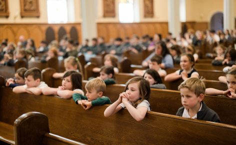 Saint Mary School students kneeling in prayer in the pews during Mass